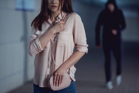 cropped view of frightened woman running away from thief in underpass