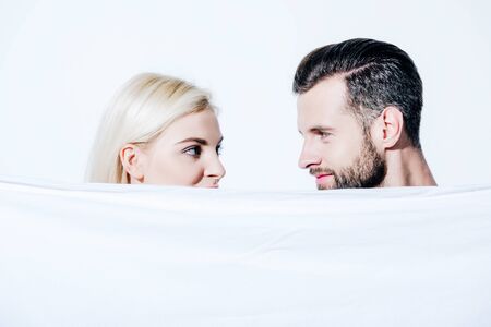 girlfriend and boyfriend looking at each other and holding blanket isolated on whiteの写真素材