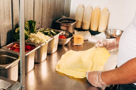 partial view of cook in gloves preparing doner kebab