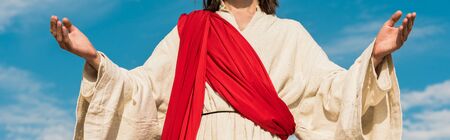 panoramic shot of jesus with outstretched hands against blue skyの写真素材