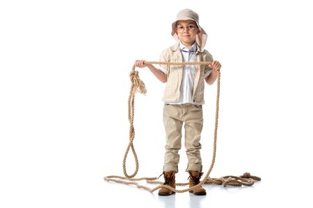 full length view of explorer kid in hat and glasses holding rope on whiteの写真素材