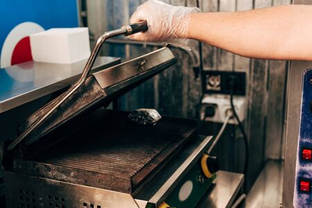 cropped view of cook in glove opening kebab grill in kitchenの写真素材