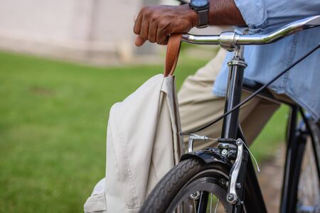 cropped view of african american man standing near bicycle with backpack