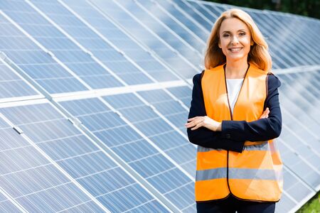 attractive businesswoman with crossed arms smiling and looking at cameraの写真素材
