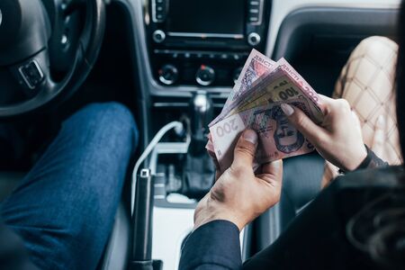 cropped view of client paying cash to woman in car