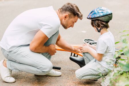 father looking at knee of son because boy fell from bicycleの写真素材