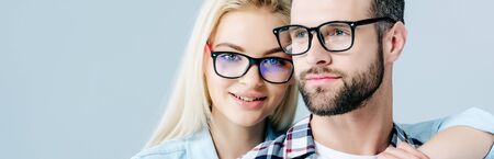panoramic shot of man and beautiful girl in glasses isolated on greyの写真素材