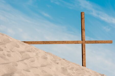 wooden cross on golden and wavy sand in desertの写真素材