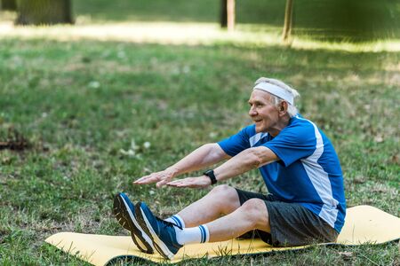 happy retired man exercising on fitness mat in parkの写真素材