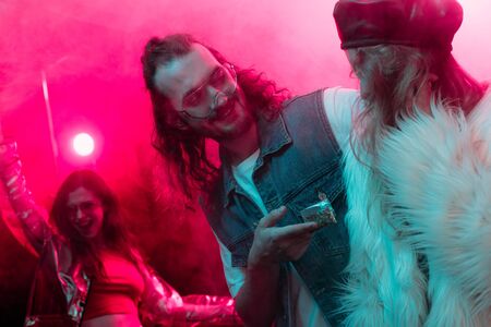 happy man giving weed in plastic zipper bag to girl in nightclub