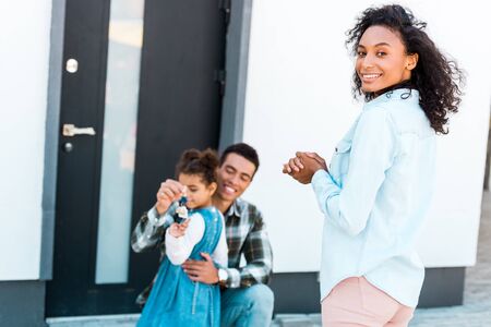 african american woman standing near man and looking at camera while father hugging daughter and holding keyの写真素材