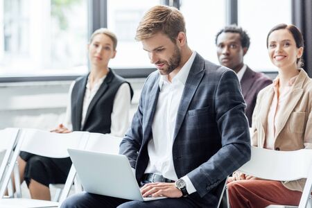 selective focus of businessman in formal wear using laptop during conference