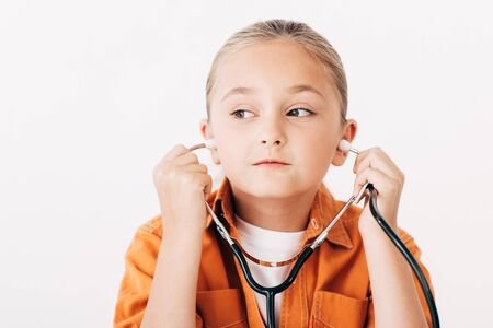 pensive child holding stethscope and looking away isolated on whiteの写真素材