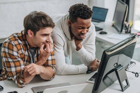 two worried multicultural programmers looking at laptop in officeの写真素材