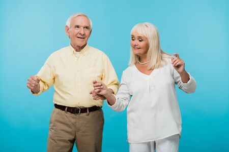 happy retired couple with grey hair gesturing isolated on blue
