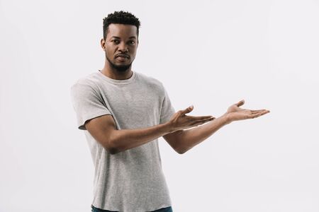 handsome african american man gesturing while looking at camera isolated on whiteの写真素材