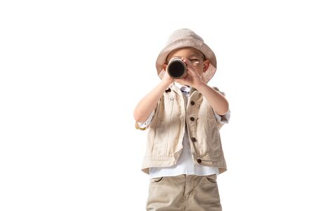 explorer boy in glasses and hat looking through spyglass isolated on whiteの写真素材