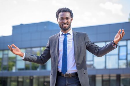 cheerful, handsome african american businessman gesturing while smiling at cameraの写真素材