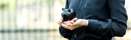 panoramic shot of woman holding black piggy bankの写真素材