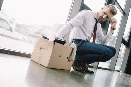 upset businessman looking at carton box in officeの写真素材