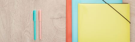 panoramic view of folders and pens on wooden tableの写真素材