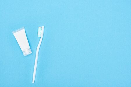 top view of white toothbrush and toothpaste isolated on blue