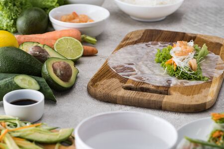 cut carrot, lettuce, noodles, shrimps and rice paper on cutting board