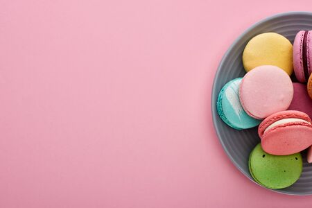 plate with multicolored delicious French macaroons on pink background with copy spaceの写真素材