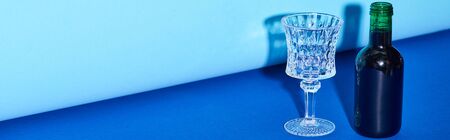 panoramic shot of glass and bottle with wine on colorful background