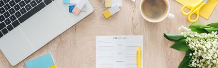 panoramic view of monthly planner, flowers, laptop and coffee cup on wooden tableの写真素材