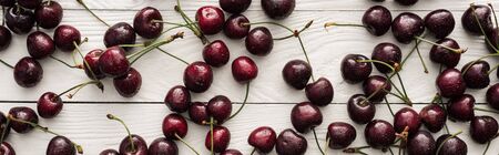 panoramic shot of fresh, sweet, red and ripe cherries with droplets on wooden surface