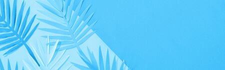 panoramic shot of paper leaves on blue minimalistic background with copy space