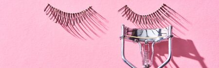 panoramic shot of false eyelashes and eyelash curler on pink backgroundの写真素材