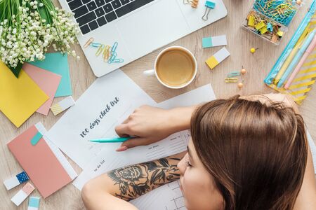 top view of woman sleeping behind wooden table with stationery, laptop and plannersの写真素材