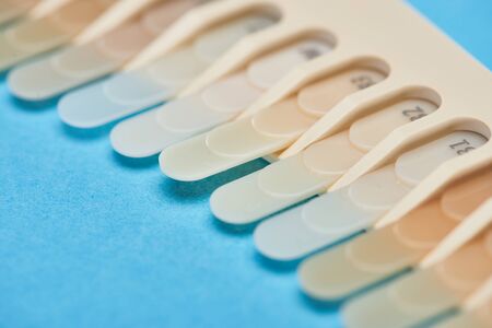 selective focus of teeth palette with different shades on blue