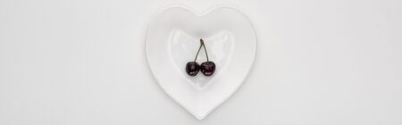 panoramic shot of fresh, sweet and ripe cherries on heart shaped plateの写真素材
