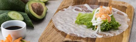 panoramic shot of lettuce, noodles and shrimps on rice paper, on cutting board