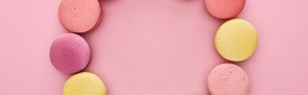 frame of multicolored delicious French macaroons on pink background, panoramic shotの写真素材