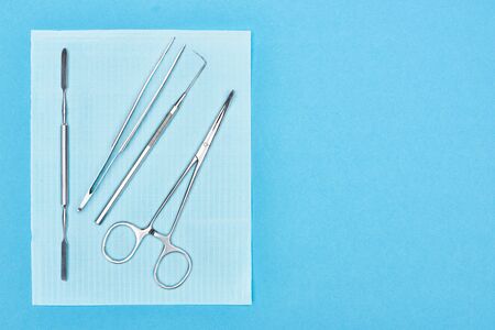 top view of stainless set with dental tools on apron isolated on blue