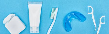 panoramic shot of toothbrush, toothpaste and teeth floss near retainer and floss sticks isolated on...