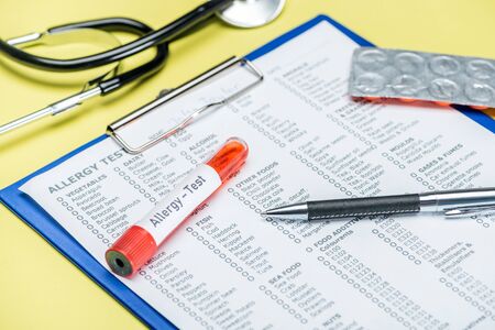 test tube and pen on allergy test results near stethoscope on yellow