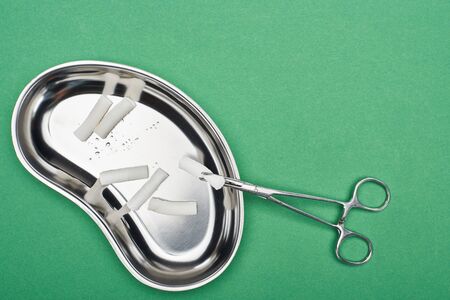 top view of scissors near metallic plate with cotton pads isolated on green