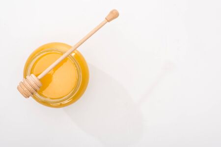 top view of jar with honey and wooden honey dipper on white background with copy spaceの写真素材