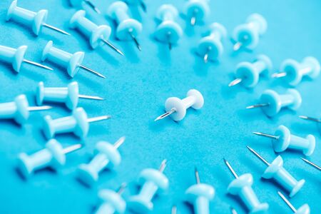 selective focus of white paper clip in middle of blue paper clips in circle on blue background,...