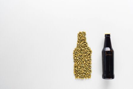 top view of bottle of dark beer near pressed hop isolated on whiteの写真素材