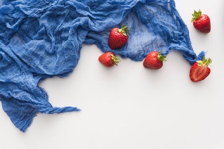 top view of sweet and whole strawberries on blue clothの写真素材
