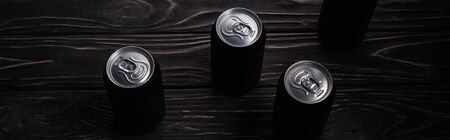 panoramic shot of black aluminum cans of beer on wooden table with copy spaceの写真素材