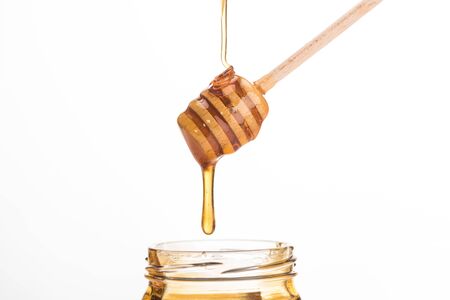 wooden honey dipper with dripping sweet honey isolated on whiteの写真素材