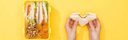 cropped view of woman holding sandwich in hands near lunch box with foodの写真素材
