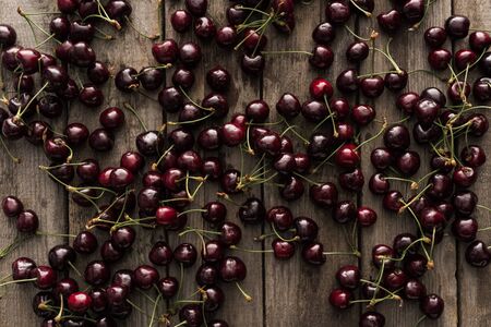 top view of red, fresh, whole and ripe cherries on wooden surface